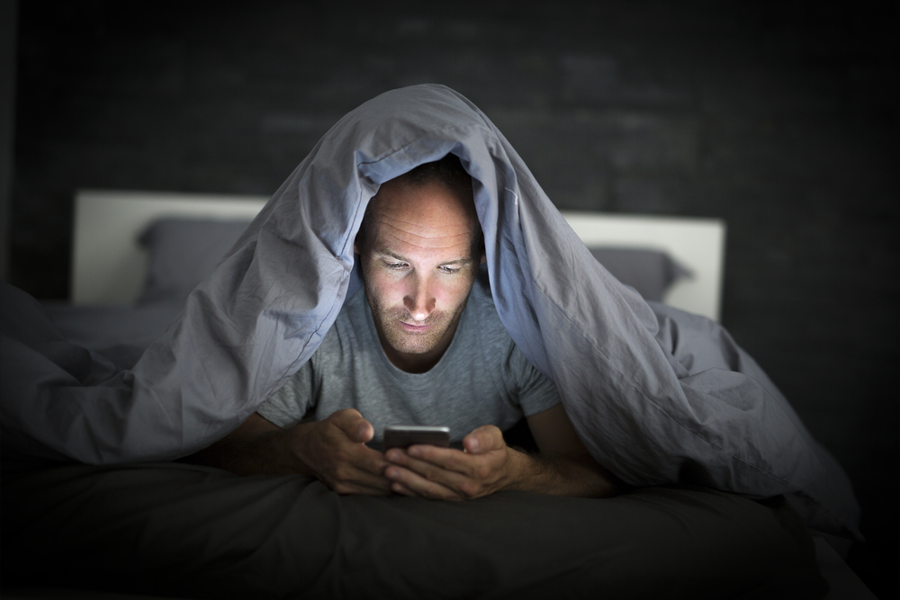 Man using phone in bed